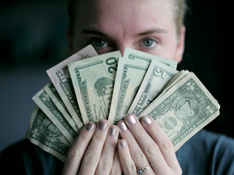 person holding fan of U.S. dollars banknote